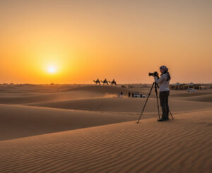 A group of friends taking photos on a large dune at sunset in the Dubai desert.