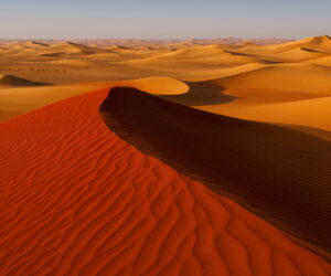 Dubai desert with striking red and golden sand dunes under a clear blue sky